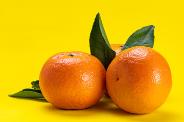 Side view of oranges with leaves isolated on yellow background with clipping path