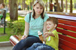 © Oleksandra - Happy family concept. Mother and son are playing in the park,  laughing and eating ice cream on a spring walk on a sunny day. Family holiday and togetherness, selective focus.