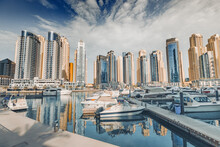Yacht And Motor Boats Parking At The Port Near Dubai Marina Mall With Row Of High Skyscrapers Residential Buildings And Hotels