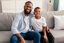 Portrait Of Black Father And Son Hugging On Couch
