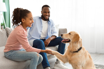 Smiling black girl playing with dog in the living room