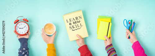 Obraz Dibond Learn new skill text with hands holding school supplies over b;ue background. Business concept of positive thinking and motivation