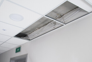 disassembled suspended ceiling and hidden wiring above it, needs repair