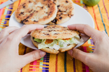 Wall Mural - Mexican eating gordita de chicharron stuffed with onion, coriander, lettuce, spicy chile sauce and cheese