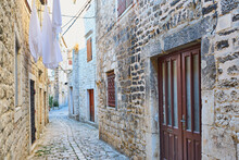 Narrow Pavements In One Of The Old Towns On The Adriatic Coast, Shiny Cobblestones And Tall Tenement Houses, Drying Clothes In The Background