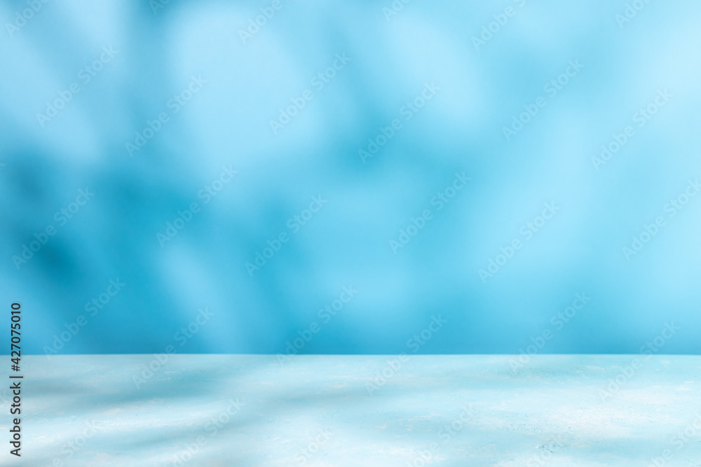 Abstract shadow on table top and blue wall background. Blurred backdrop with copy space. - obrazy, fototapety, plakaty 