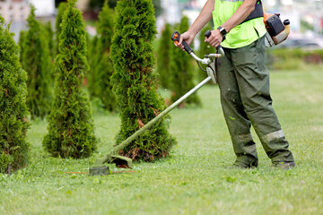 man gardener worker changing landscape with string lawn trimmer