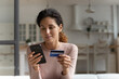 © fizkes - Focused concentrated millennial latina female using mobile telephone to make easy safe payment online in electronic bank system. Young lady client spend money from credit card in virtual shop via cell