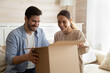 © fizkes - Smiling young man and woman have fun open unpack box shopping online together on internet. Happy multiracial couple buyers feel excited with good delivery service, unbox package with order.