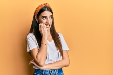 Wall Mural - Beautiful brunette young woman wearing casual white t shirt looking stressed and nervous with hands on mouth biting nails. anxiety problem.