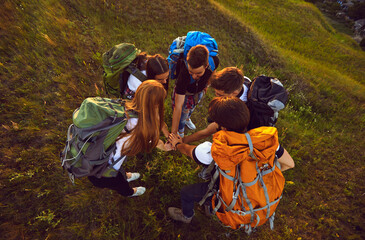 Wall Mural - handshake of young smiling tourists hikers standing in circle and hiking together on nature