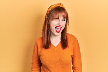 Poster - Redhead young woman wearing casual orange sweater winking looking at the camera with sexy expression, cheerful and happy face.