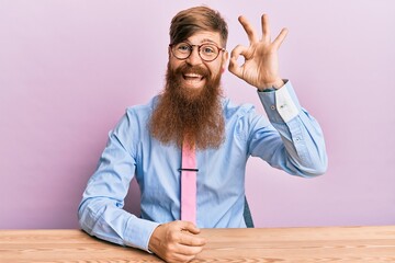 Sticker - Young irish redhead man wearing business shirt and tie sitting on the table smiling positive doing ok sign with hand and fingers. successful expression.