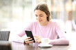 © Antonioguillem - Woman using smart phone seated in a coffee shop
