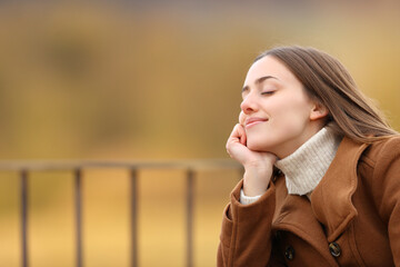 Wall Mural - Woman relaxing with closed eyes in a balcony in winter