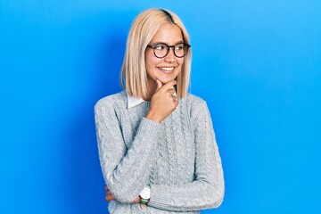 Wall Mural - Beautiful blonde woman wearing glasses with hand on chin thinking about question, pensive expression. smiling with thoughtful face. doubt concept.