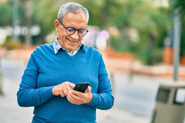 Wall Mural - senior grey-haired man smiling happy using smartphone at the city.