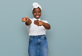 Canvas Print - Young african woman with turban wearing hair turban over isolated background pointing to you and the camera with fingers, smiling positive and cheerful