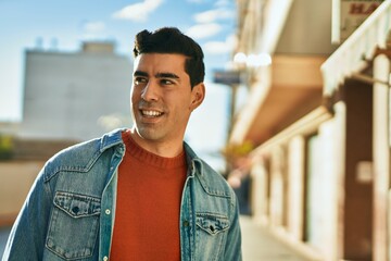 Young hispanic man smiling happy standing at the city.