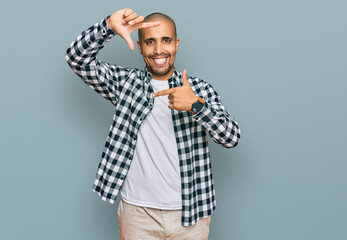 Poster - Hispanic adult man wearing casual clothes smiling making frame with hands and fingers with happy face. creativity and photography concept.