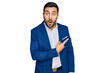 © Krakenimages.com - Young hispanic man wearing business jacket surprised pointing with finger to the side, open mouth amazed expression.
