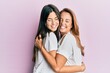 © Krakenimages.com - Beautiful hispanic mother and daughter smiling happy hugging over isolated pink background.