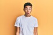 © Krakenimages.com - Young handsome african american man wearing casual white tshirt scared and amazed with open mouth for surprise, disbelief face