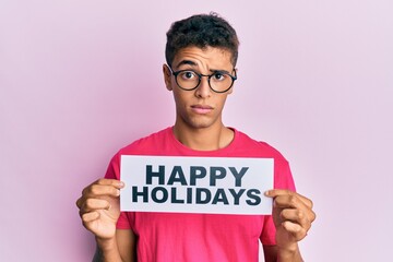 Sticker - Young handsome african american man holding happy holidays message skeptic and nervous, frowning upset because of problem. negative person.