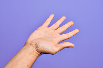 Wall Mural - Hand of caucasian young man showing fingers over isolated purple background presenting with open palm, reaching for support and help, assistance gesture