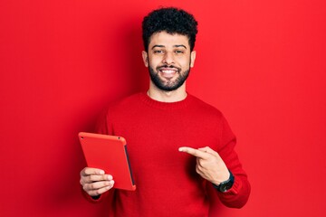 Sticker - Young arab man with beard using touchpad device smiling happy pointing with hand and finger