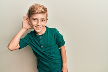 Wall Mural - Little caucasian boy kid wearing casual clothes smiling with hand over ear listening and hearing to rumor or gossip. deafness concept.