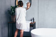 © undrey - Woman washes in front of the mirror, applying foam to her face
