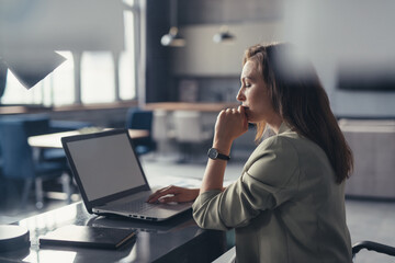 Business woman in a suit working with a laptop at her desk in her home office