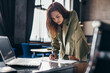 © undrey - Woman entrepreneur stands and writes leaning on desk