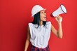 © Krakenimages.com - Young african american worker woman screaming using megaphone over isolated red background.