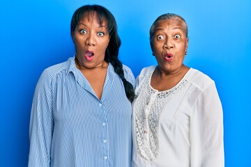 Poster - Hispanic family of mother and daughter hugging together with love scared and amazed with open mouth for surprise, disbelief face