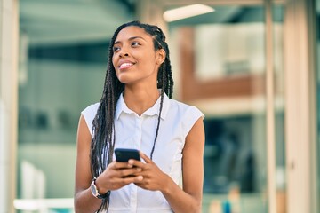 Poster - Young african american woman smiling happy using smartphone at the city.