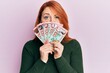 Beautiful redhead woman holding 100 new zealand dollars banknote skeptic and nervous, frowning upset because of problem. negative person.