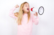 beautiful caucasian little girl wearing pink hoodie over white background communicates shouting loud holding a megaphone, expressing success and positive concept, idea for marketing or sales.
