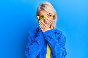 Sticker - Young blonde girl wearing casual clothes and glasses shocked covering mouth with hands for mistake. secret concept.