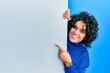 © Krakenimages.com - Young hispanic woman with curly hair holding blank empty banner smiling happy pointing with hand and finger