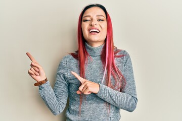 Young caucasian woman wearing casual clothes smiling and looking at the camera pointing with two hands and fingers to the side.