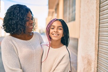 Sticker - Beautiful african american mother and daughter smiling happy and hugging. Standing with smile on face standing at the city.