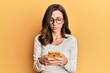 © Krakenimages.com - Young brunette woman using smartphone over yellow background relaxed with serious expression on face. simple and natural looking at the camera.