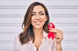 © Krakenimages.com - Young hispanic woman smiling happy holding red hiv ribbon standing at the city.