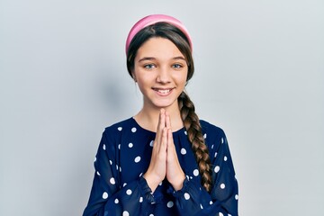 Wall Mural - Young brunette girl wearing elegant look praying with hands together asking for forgiveness smiling confident.