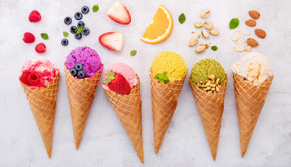 Leinwandbilder - Various of ice cream flavor in cones blueberry ,pistachio ,almond ,orange and cherry setup on white stone background . Summer and Sweet menu concept.