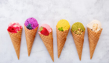 Various of ice cream flavor in cones blueberry ,pistachio ,almond ,orange and cherry setup on white stone background . Summer and Sweet menu concept.