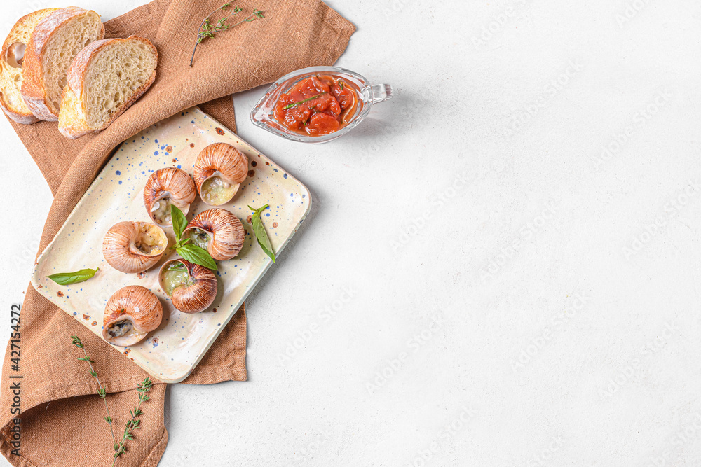 Plate with tasty snails on light background