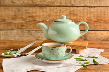 Cup and teapot of green tea on wooden background